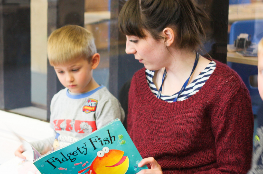 Nursery teacher reading to pupil