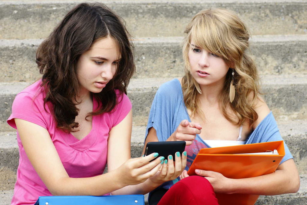 Students looking at a mobile phone with very serious faces