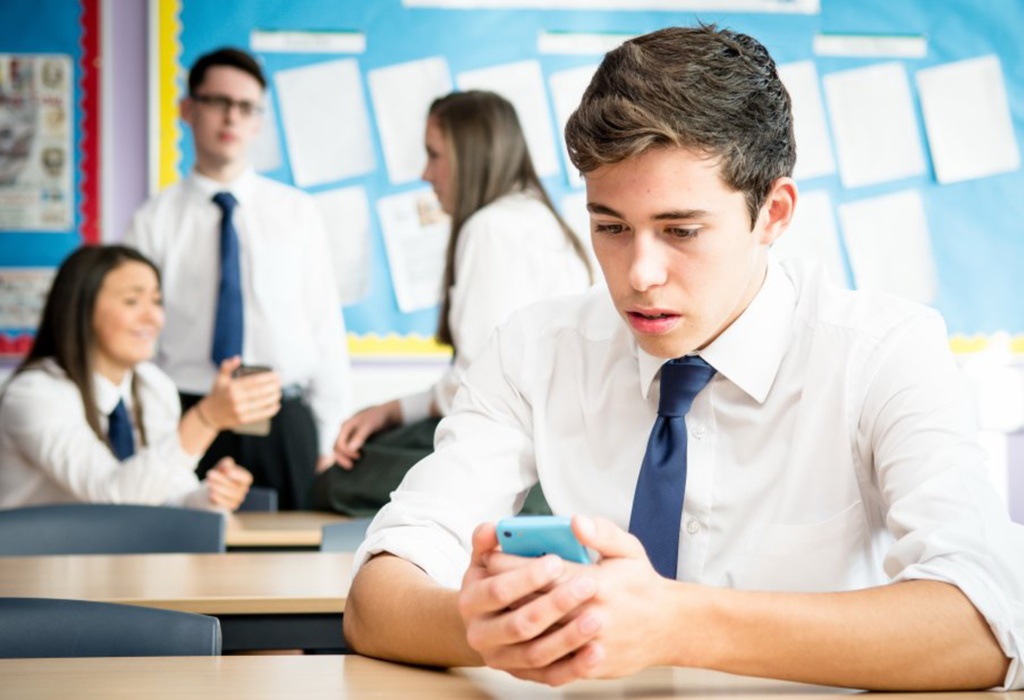 Boy looking at his mobile phone in the classroom