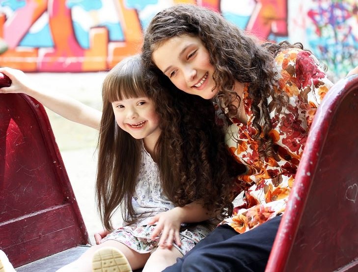 Teenage girl with younger downs syndrome girl having fun