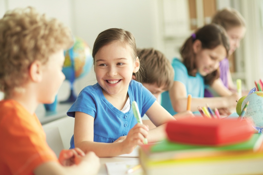 primary girl smiling sitting at desk