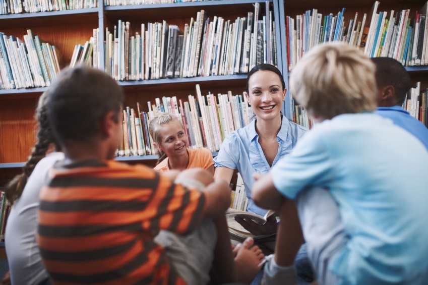 Teacher sitting with primary students in library