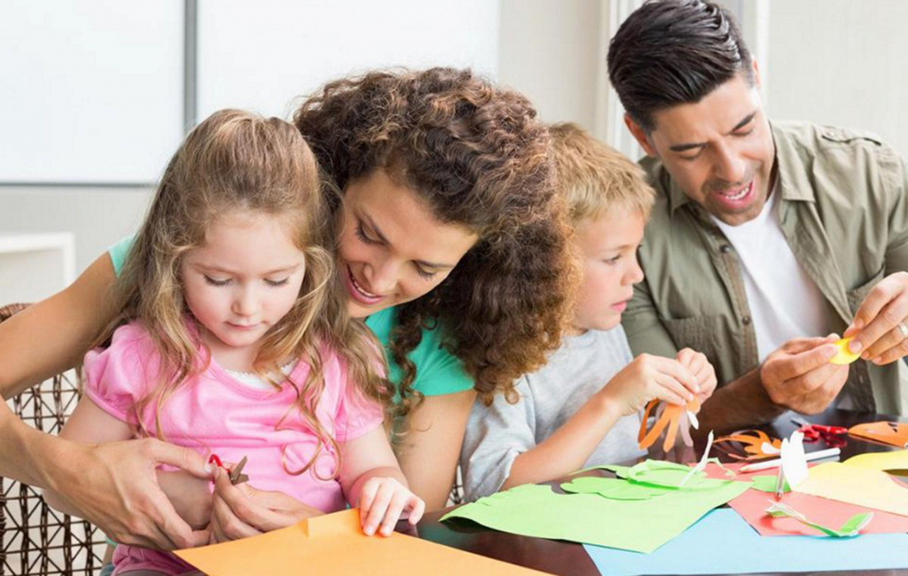 mom and dad with children cutting out shapes