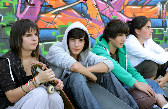 four teenagers sitting by graffiti wall
