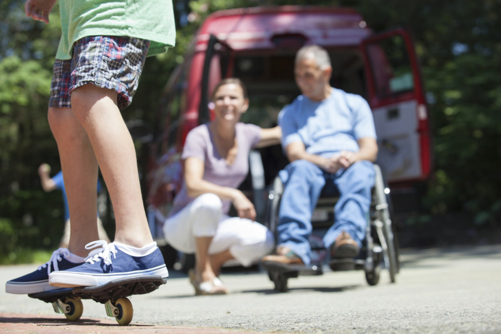 boy on skateboard with disabled parent in background