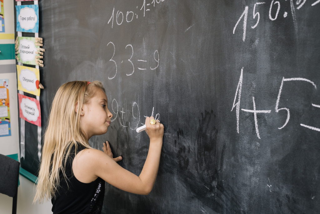 Young girl writing on black board
