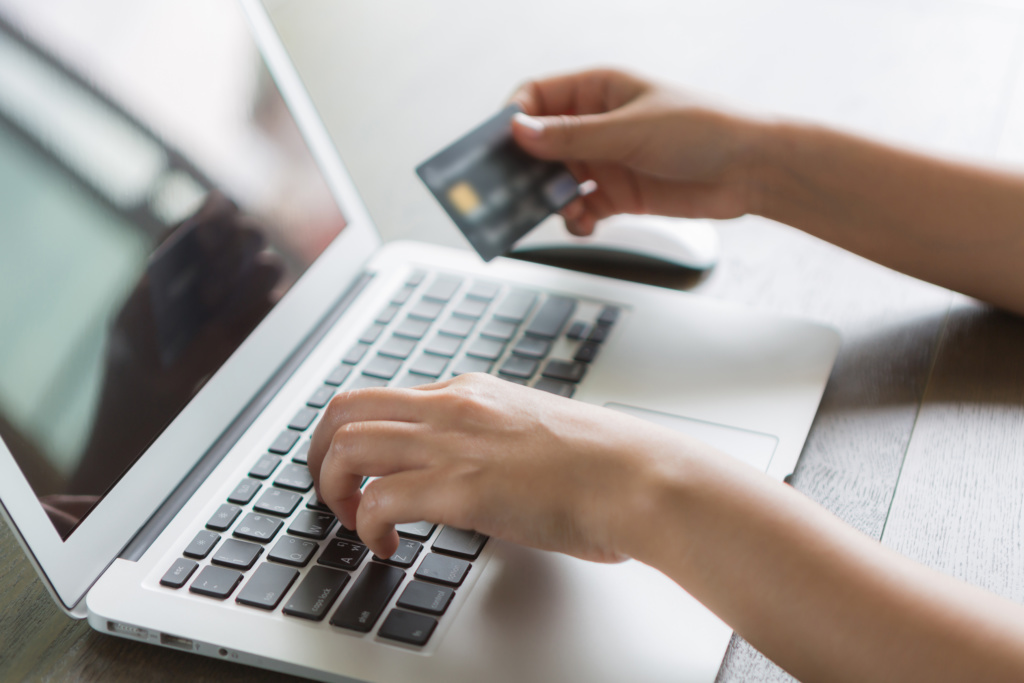 Hands holding a credit card and using laptop computer for online