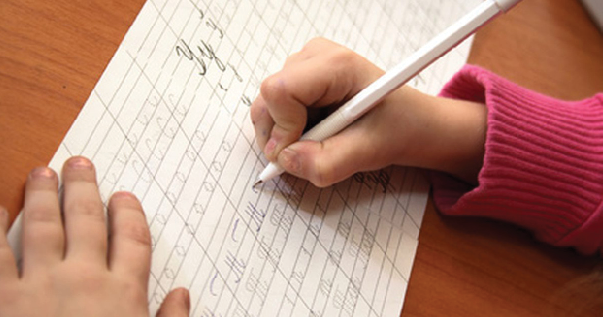 Child's hand writing letters with pencil