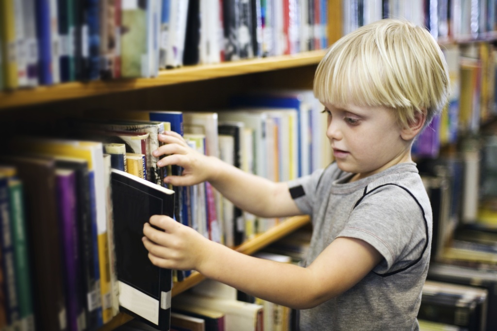 Young child taking book out of library shelf