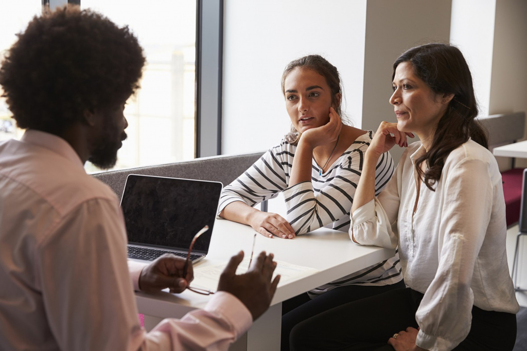 three adults at desk in business