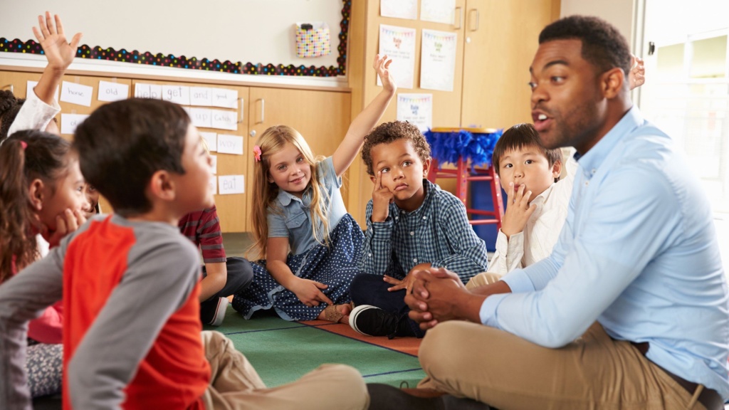 nursery children with teacher sitting in circle onfloor 