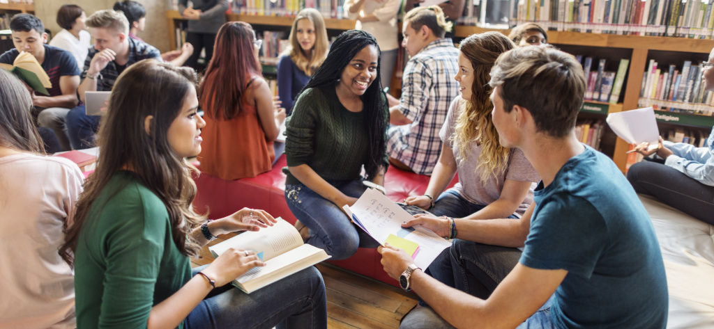 Group teenagers in discussion sitting on low chairs 