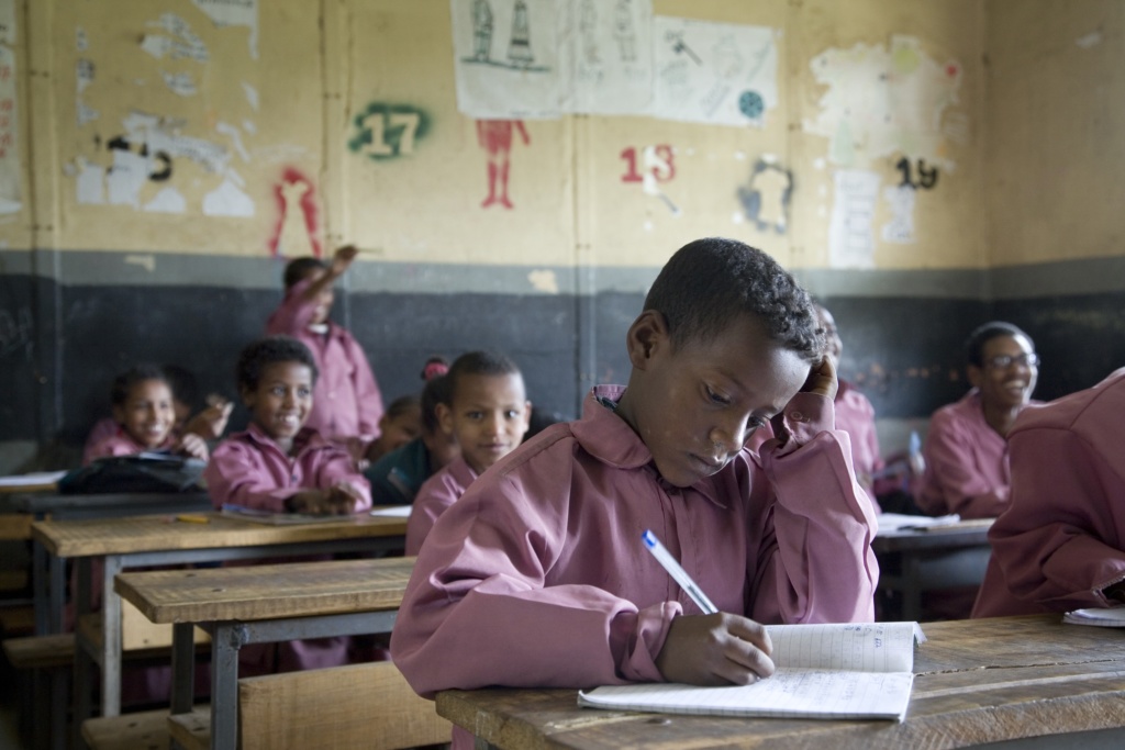 Young child at school in Ethiopia sitting at desk writing