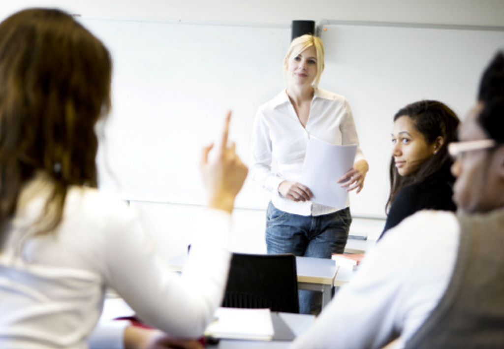 Student with hand up as teacher and students look at her