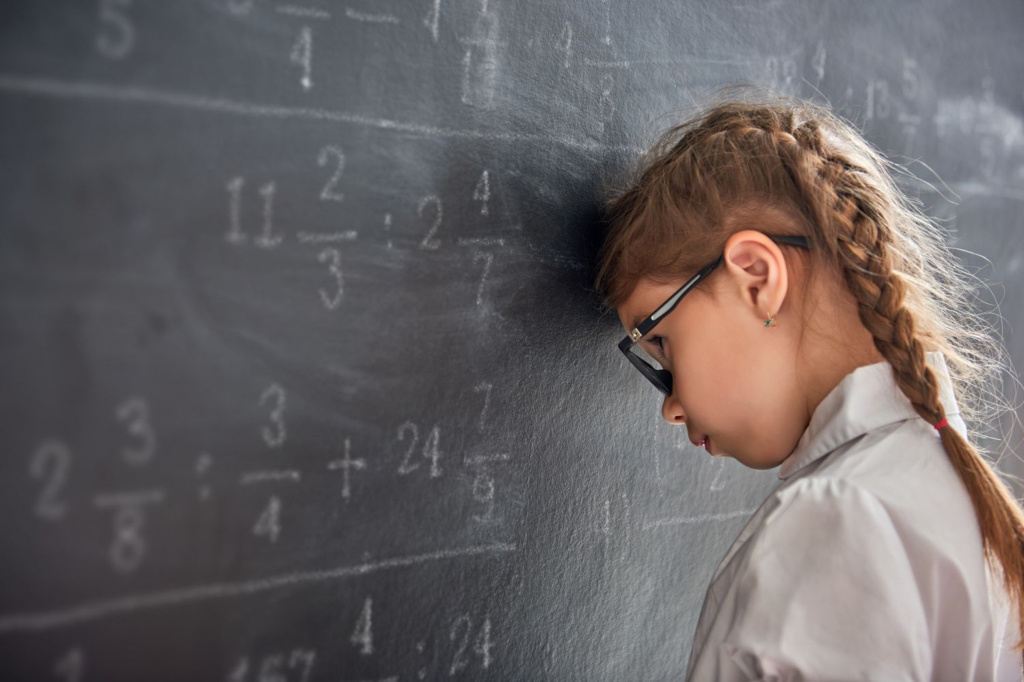 Young pupil struggling with calculations on black board