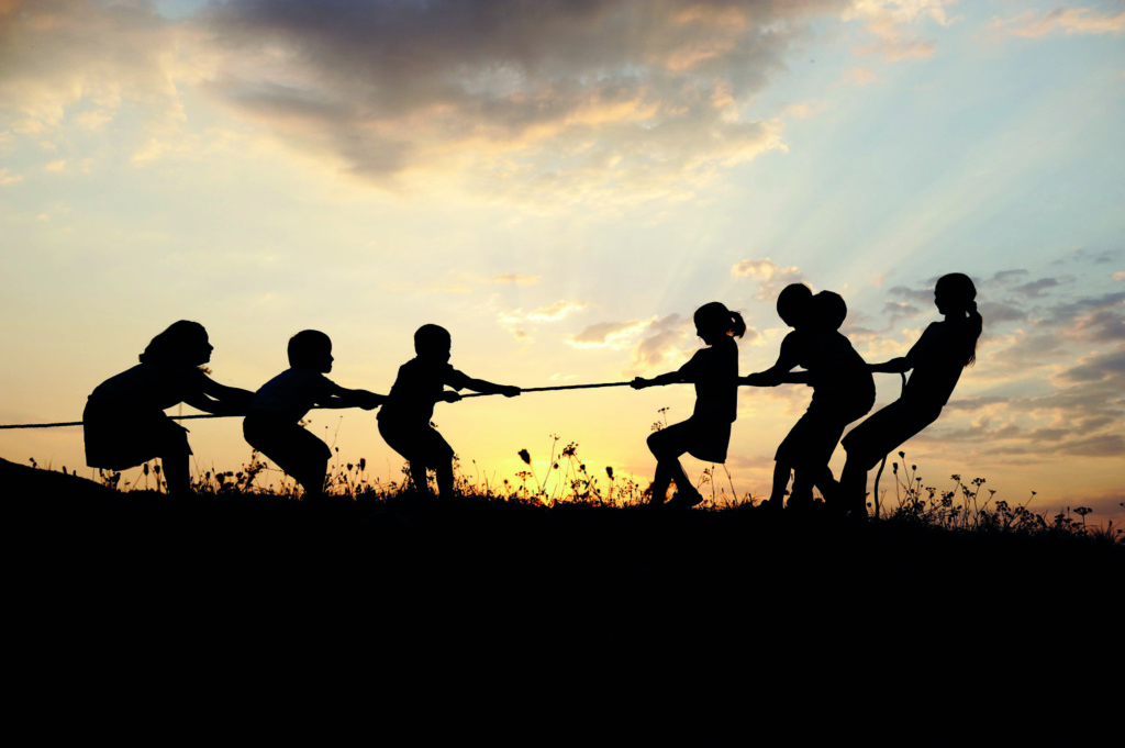 Children playing tug of war in a field.