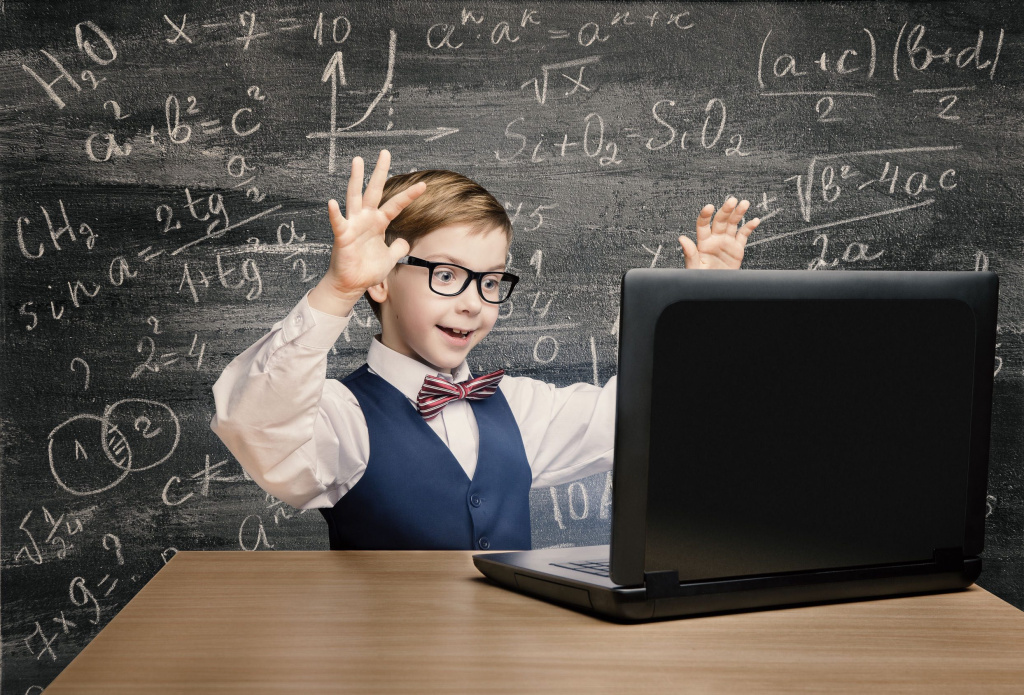Kid looking at laptop, child with notebook, little boy mathematics formula on chalkboard