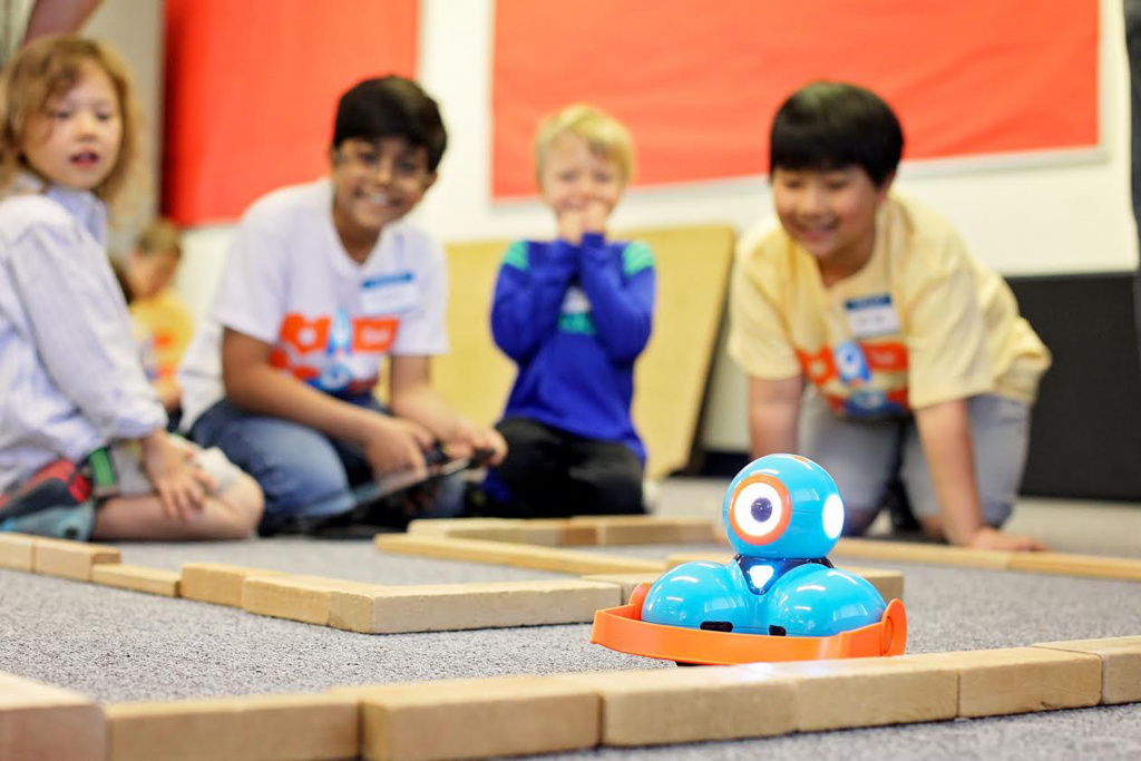 Young pupils playing with robot