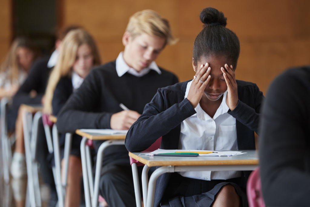 Anxious teenage student struggling in an exam hall.