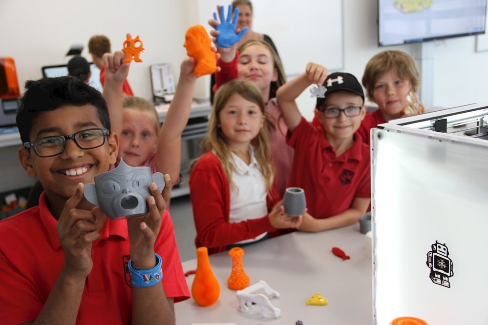 Six primary aged children holding up masks they have made on 3D printers