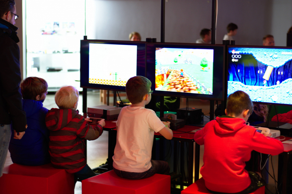 4 young children at a museum looking at screens