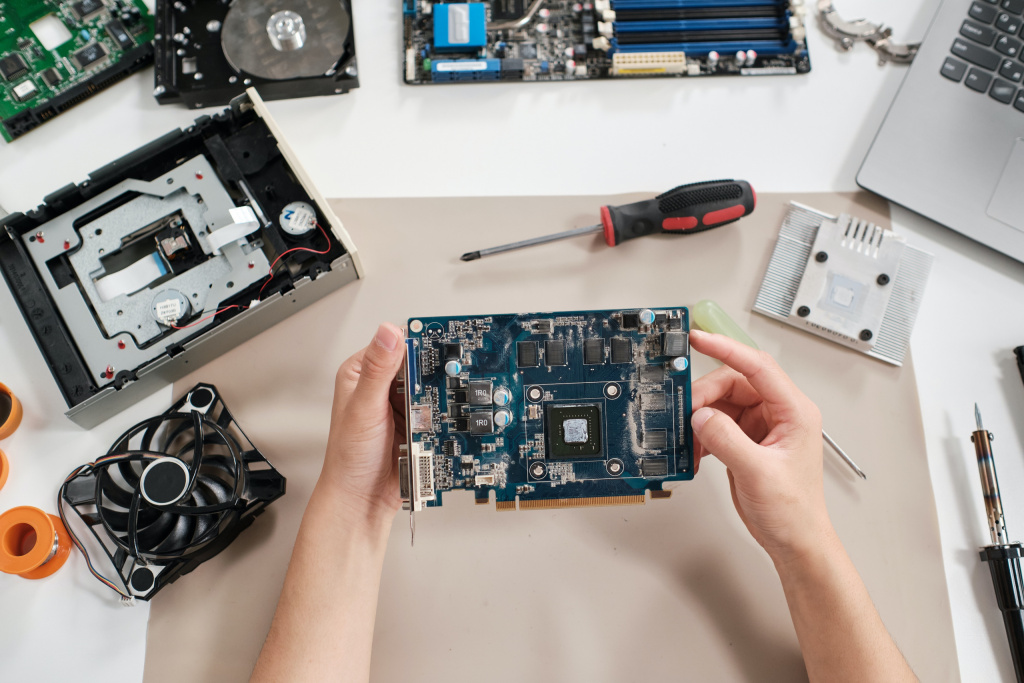 View of the hands of a young person repairing a computer circuit board.