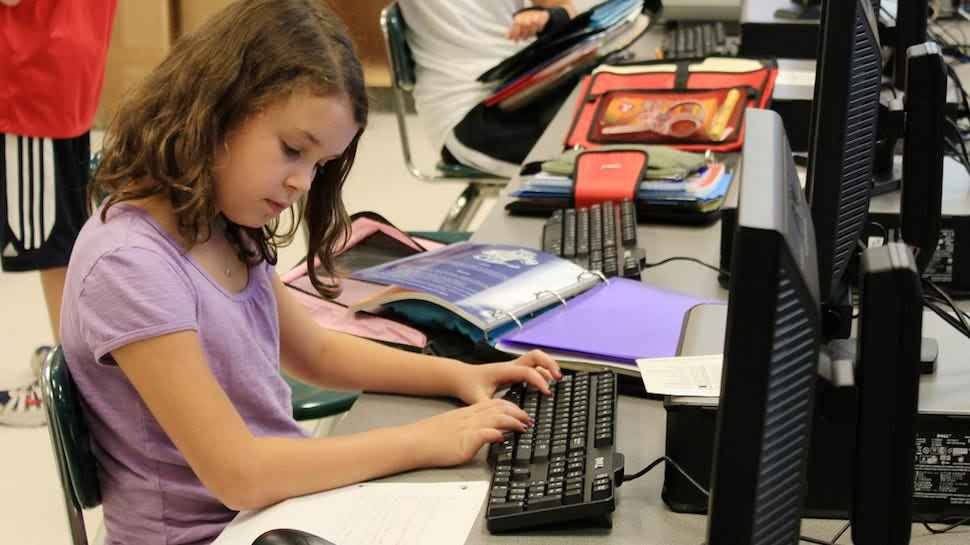 Elementary school girl using a desktop computer.