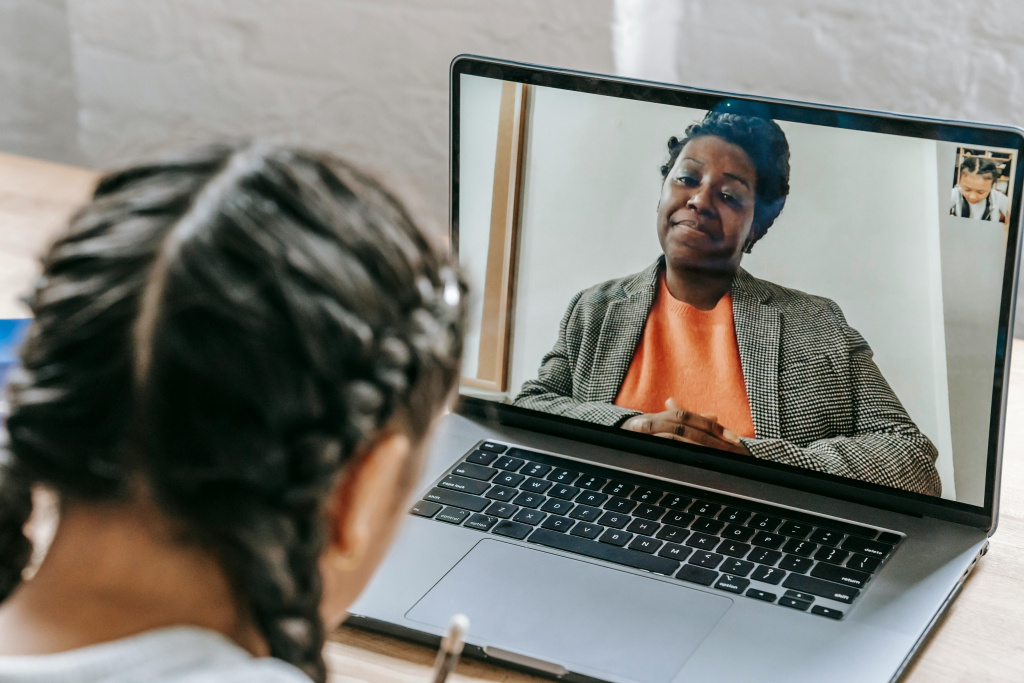 Black female teacher delivering a lesson remotely via laptop.