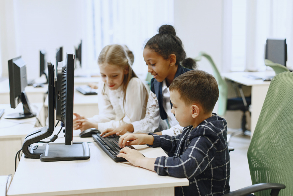 Smiling primary school children gathered around a computer