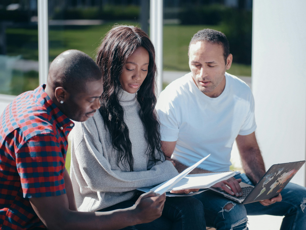 Three teachers reviewing research documents outside