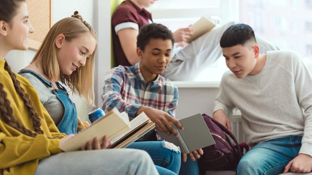 High school students reading books in a hallway.