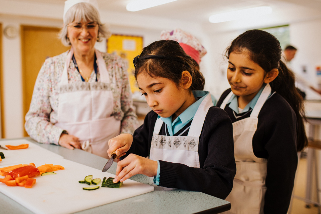 Primary school girl cutting cucumber in a food tech lesson