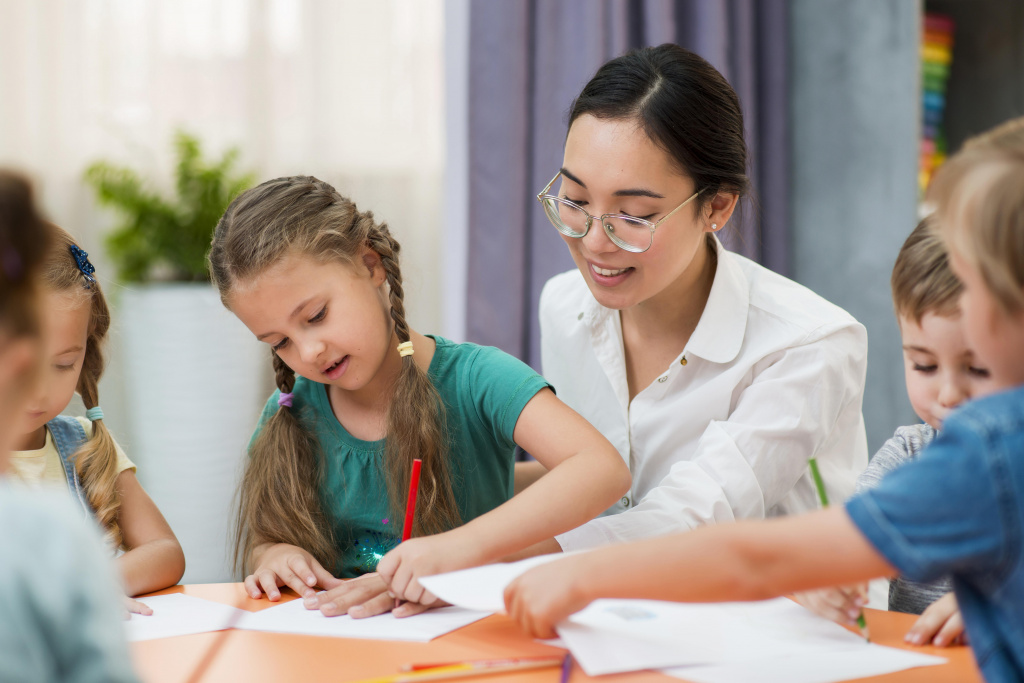 Teaching assistant helping her students in the classroom.